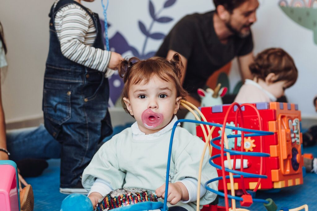 Cute young child with pacifier playing in a colorful indoor playroom setting.